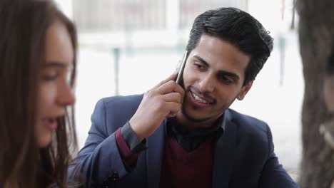 Serious-mixed-race-man-talking-on-phone-while-having-meeting